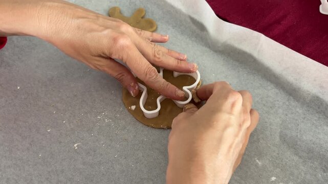 Manos cortando galletas con molde de jengibre