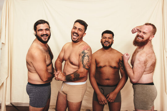 Cheerful men flexing their natural bodies in a studio