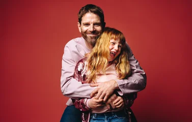 The warm family portrait shows a father and daughter laughing together with a hug © Jacob Lund