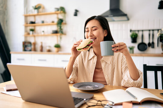 Woman eating and drinking while working at home.
