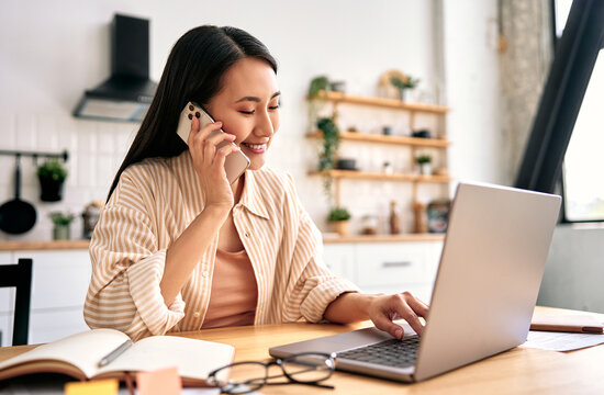 Young woman working from home with phone and laptop.