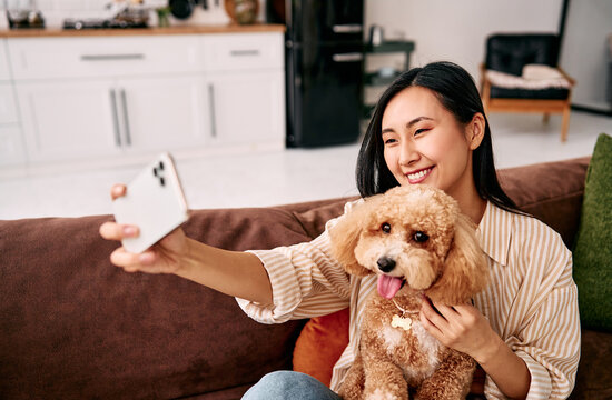 Woman taking selfie with dog at home.