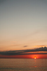 Obraz premium Calm sunset over a tranquil sea paints warm orange light across the water and horizon, inviting reflection and peaceful mood.
