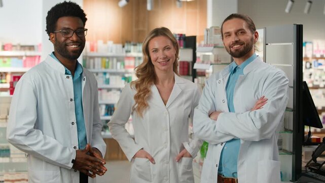 Multiethnic doctors pharmacists three colleagues talking happy posing smiling in pharmacy in hospital diversity professional team group therapists co-workers smile talk optimistic looking at camera
