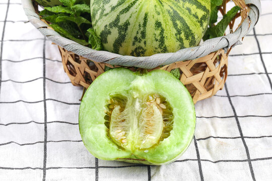 Fresh Winter Melon Cut in Half with Whole Melons in Wicker Basket