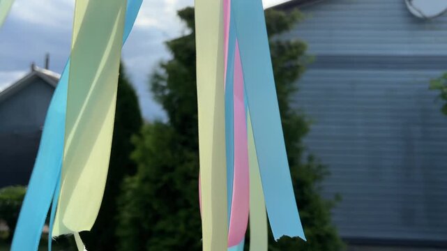 Vibrant colorful ribbons hanging on a rope waving in the breeze during a festive summer holiday celebration in the yard