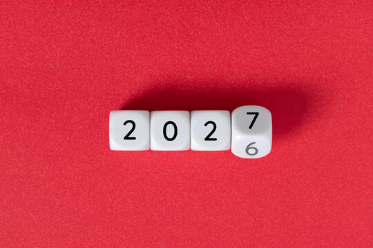Year 2026 changing to 2027 on dice, glitter festive red background. New year change concept