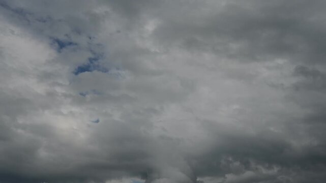 time lapse of dark ragged clouds against grey stormy sky with small blue opening