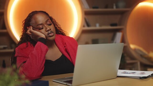 Overworked Black businesswoman working on laptop in office, feeling exhaustion