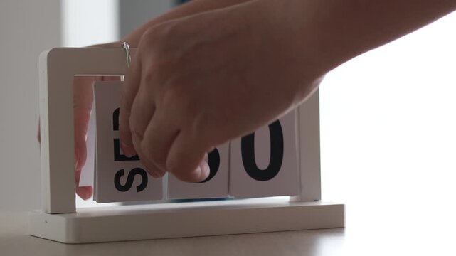 Hand flipping wooden desktop calendar from September 30 to October 1, concept of new month, schedule, time change, and date planning.