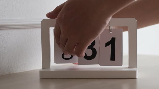 Hand flipping wooden desktop calendar from October 31 to November 1, concept of new month, time management, schedule planning, and date change.