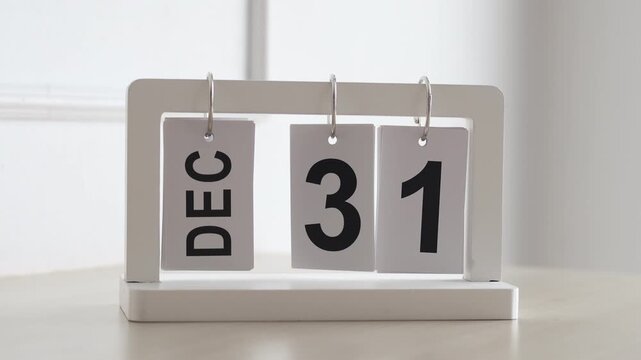 Hand flipping wooden desktop calendar from December 31 to January 1, concept of happy new year, countdown, new beginning, and time change.