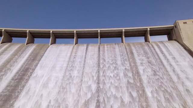 Dam spillway releasing water. Ascending aerial view. Water discharge from the upper section of a gravity dam. Rules Dam. Spain.