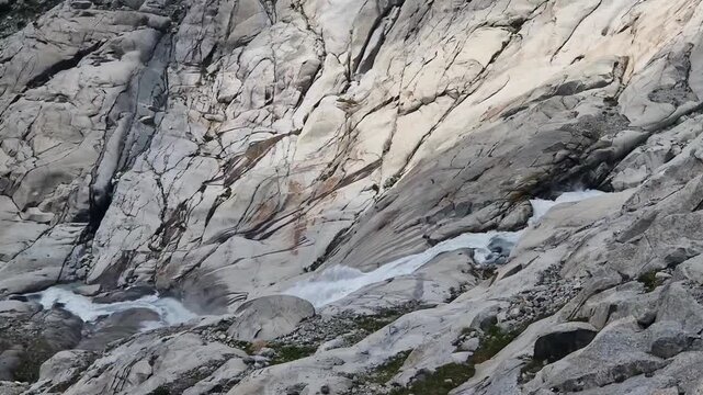 Mountain river born from the rhone glacier melting, flowing rapidly over granite rocks in the alps