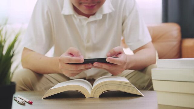 Student Distracted by Mobile Phone While Studying and Reading Book at Home.