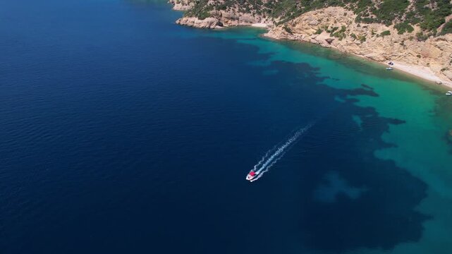 Drone aerial of a Aliki Beach secluded Mediterranean bay on Thassos, Greece with clear blue water, sandy shore, paddleboards, swimmers and stunning natural scenery.