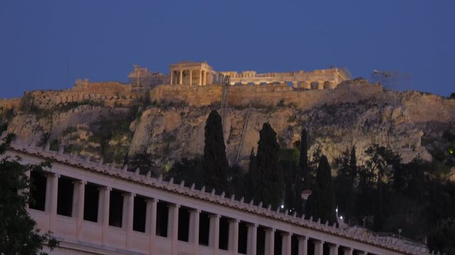 Illuminated Acropolis and Parthenon dominate the Athens skyline above the classical Stoa of Attalos at dusk.