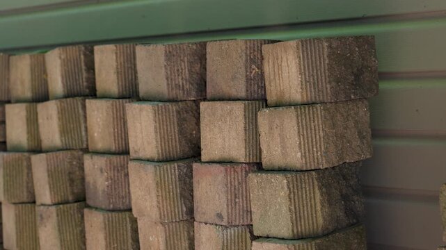 A stack of builder bricks lined up in the shade for storage.