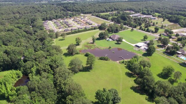 Aerial video of some fields and houses in Wooster Arkansas. Camera flies over a pond.
