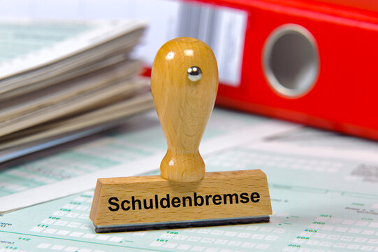 Ein Holzstempel ist beschriftet mit dem Aufdruck: Schuldenbremse