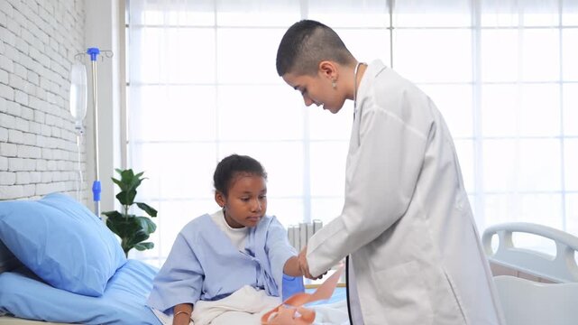 Caucasian female doctor wounding bandage around of little African American girl arm in hospital room