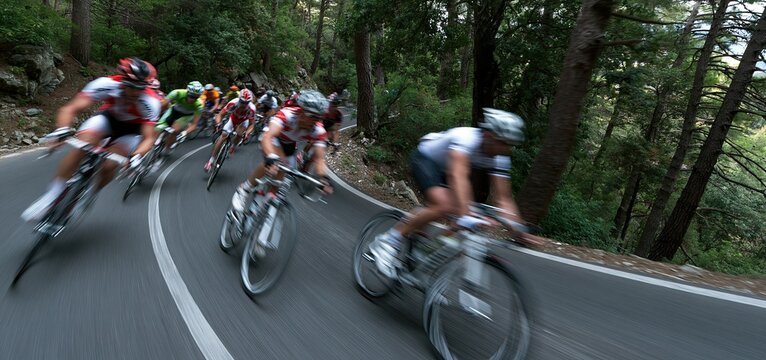 Cyclists speeding down a curving forest trail, showcasing endurance and excitement in mountain biking.
