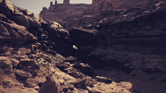 shadowed ravine between towering rock walls, cool tonal contrast, deep cavity opening into shaded chasm, textured strata and scattered scree