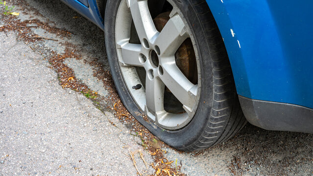 Flat Car Tire Caused by Vandalism in a City &ndash; Vehicle Damage and Crime Concept