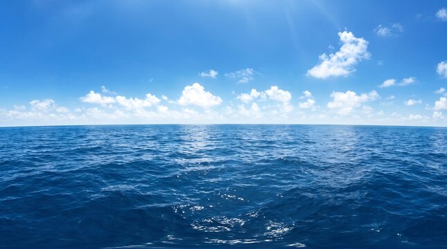 Stunning panoramic view of the vast deep blue ocean under a bright sunny sky with fluffy white clouds and calm water horizon