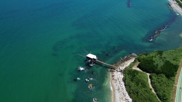 Broad aerial of a fishing hut built over water at the beach 4k drone