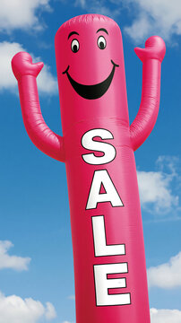 Wacky pink waving inflatable arm flailing tube man, dances against a vivid blue sky. Air dancer.