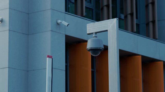 Security camera mounted outside modern building with clean architectural lines and urban surveillance setting