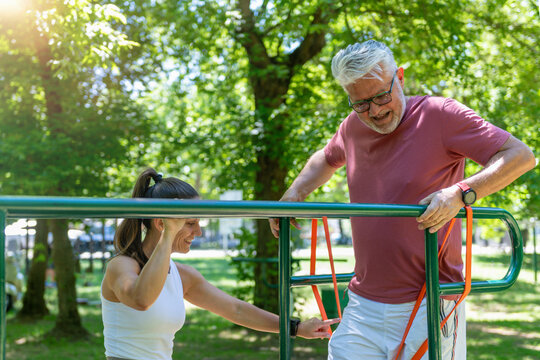 Functional strength exercise. Senior man doing a functional strength exercise on outdoor parallel bars with professional instruction to develop posture, coordination, muscular endurance 