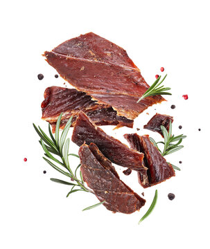 Sliced of smoked beef jerky with rosemary and allspice in the air isolated on a transparent background