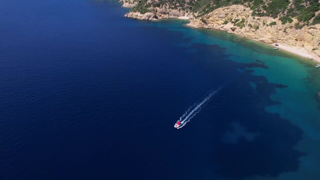 Aerial view of a fast motor yacht cutting through crystal-clear blue water. Vibrant textures, dynamic waves, powerful motion create the perfect visual for themes of luxury, freedom, vacation.