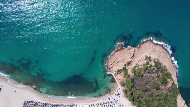 Beautiful aerial view of a sandy beach with crystal clear sea, turquoise water and visitors enjoying swimming and paddleboarding on Thassos Island, Greece.