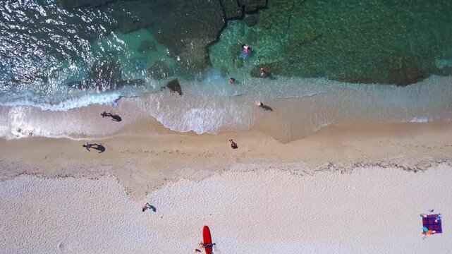 Aerial drone of a peaceful beach in Thassos, Greece, featuring transparent turquoise water, paddleboards, swimmers and a beautiful Mediterranean coastline.