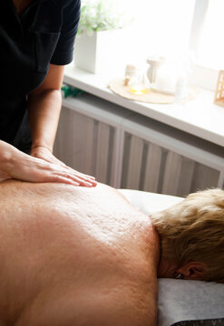 Professional massage therapist performing a relaxing back massage in a modern wellness salon. Massage treatment for relaxation, stress relief and body care.