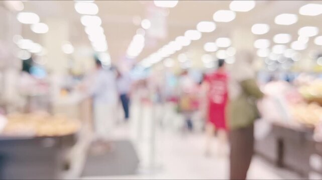 Blurred, out-of-focus video of shoppers walking in a supermarket with bokeh lighting in the background.