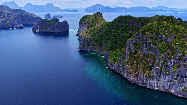 Aerial view of dramatic limestone cliffs rising from turquoise waters in the Bacuit Archipelago, Philippines.