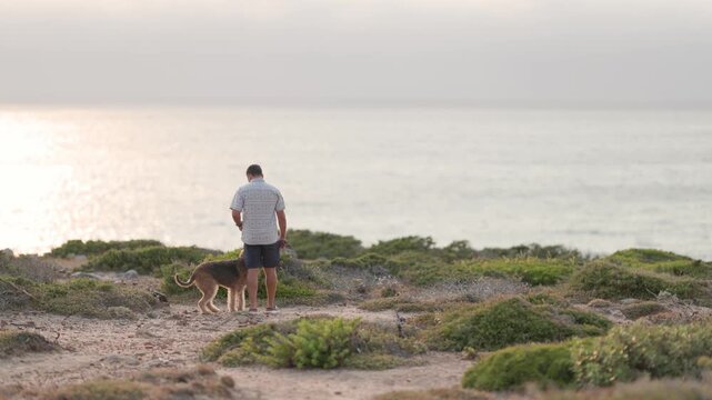 Man walking his airedale terrier dog along a scenic coastal path