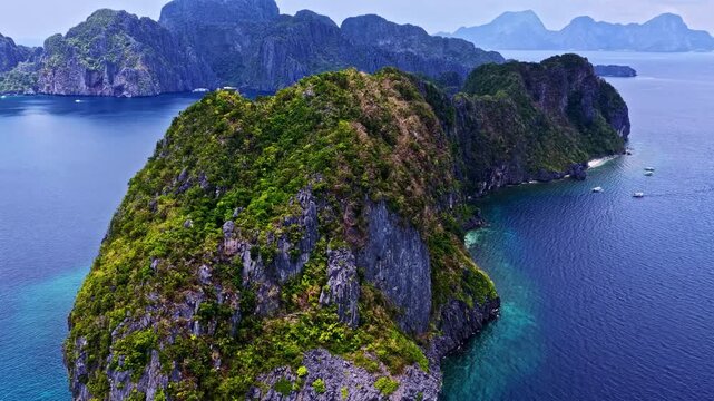 Aerial view of lush green limestone karst island surrounded by turquoise waters and rocky cliffs in the Philippines.