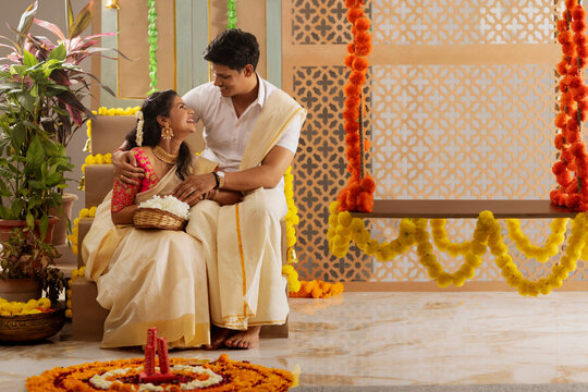 South Indian couple decorating house with flower garland to celebrate Onam