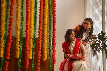 Obraz premium Portrait of two Bengali sister in traditional outfit having fun during decoration on the occasion of Durga Puja