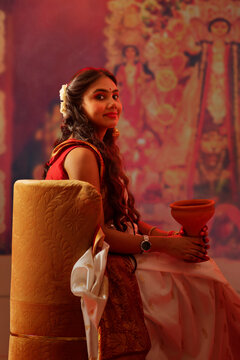 Portrait of young Bengali woman sitting with Dhunuchi in Durga puja pandal