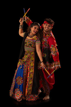 Portrait of happy young couple performing Dandiya Raas during Navratri celebration