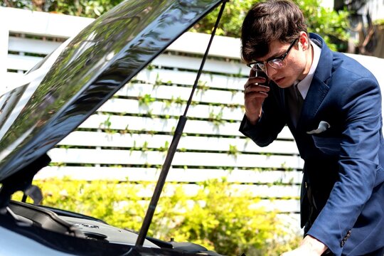 Man inspects car engine roadside.