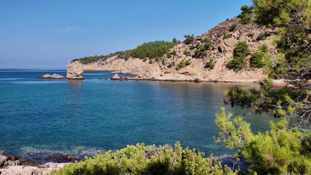 Picturesque sea bay overlooking cliffs and rock formations on a sunny day overlooking the crystal clear sea off the coast of Thassos island, Greece