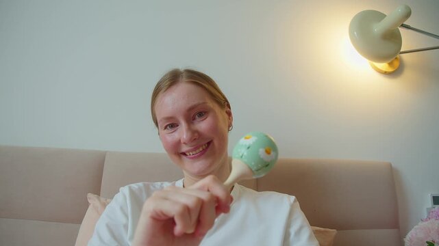 POV view shows mother moving rattle before infant during playful interaction. Toy motion encourages visual tracking, attention, sensory engagement, curiosity, early learning, and warm communication.
