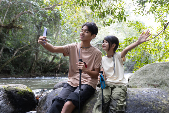Asian Teenage Boy and Younger Sister Taking Selfie During Forest Hiking